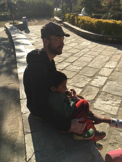 A man sits on a ledge with a young boy leaning against him. 